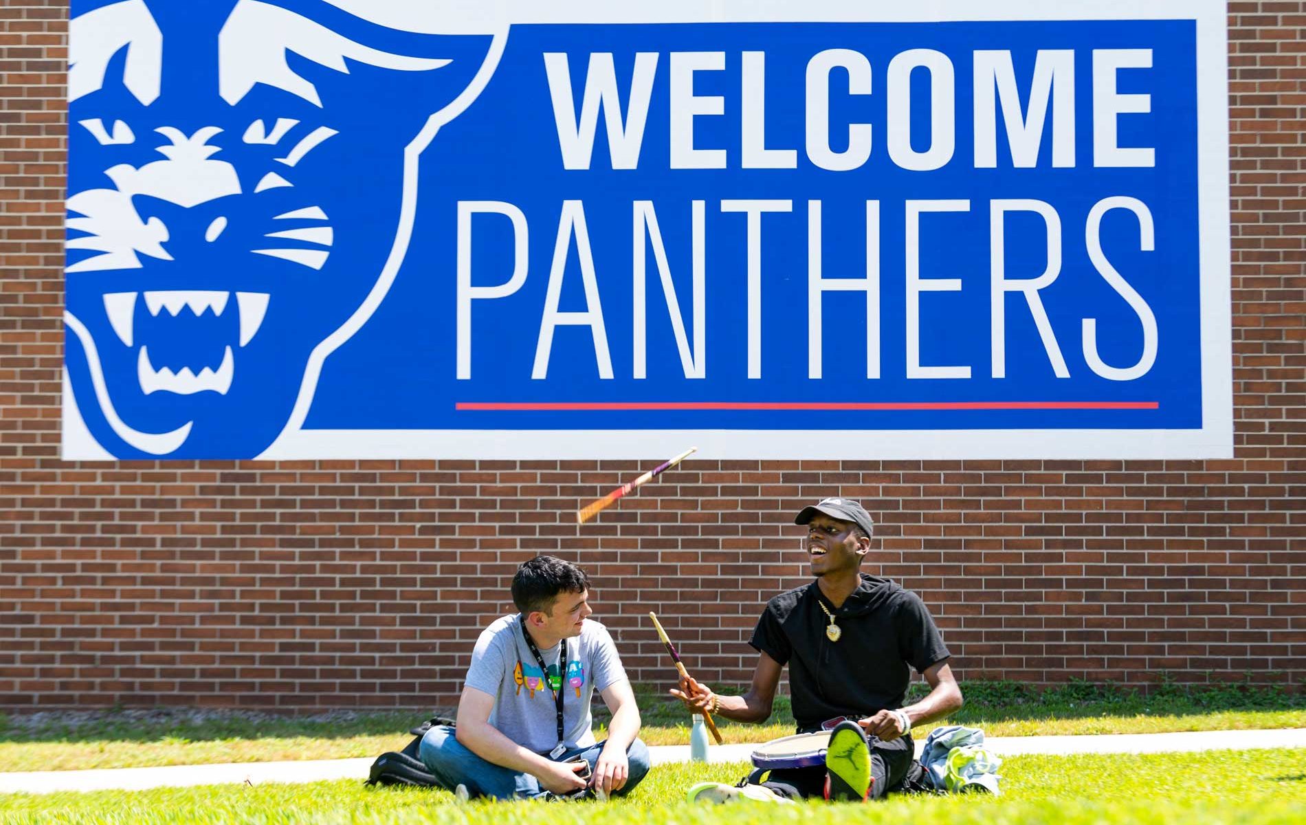 Students conversing on campus in front of the Welcome Panthers sign
